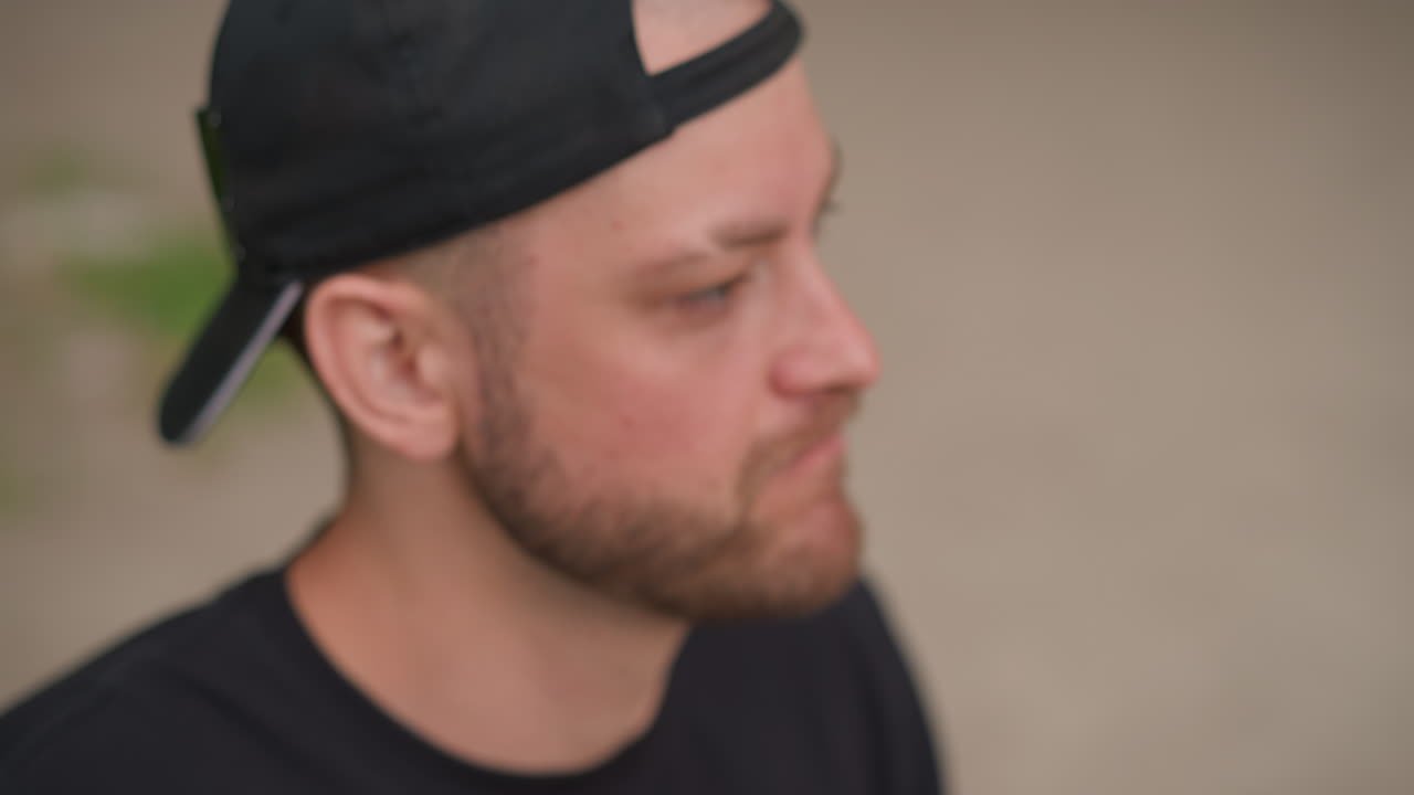 Closeup Emotion Caucasian Man Touching Face And Rubbing Temples, Yawning And Grimace, Raw Vulnerability And Frustration Shifting To Relief, Backward Cap And Beard, Street Background Conveys Candid