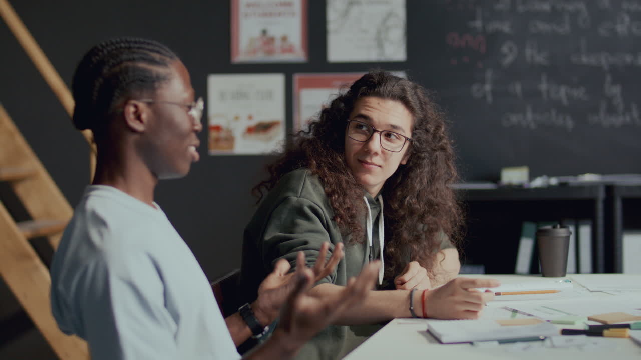 dos compañeros de clase de la universidad multiétnicos charlando durante la lección de inglés
