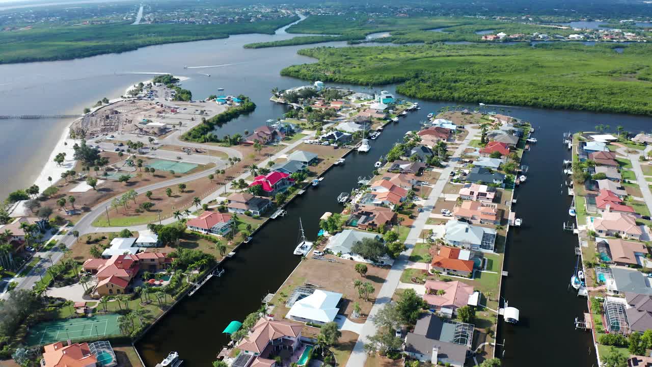Quartiere con case che costeggiano stretti canali pieni di barche, adiacente a foreste di mangrovie e a una spiaggia sabbiosa sotto un cielo limpido in Florida
