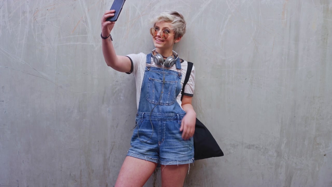 Giovane donna che si scatta un selfie contro un muro di cemento