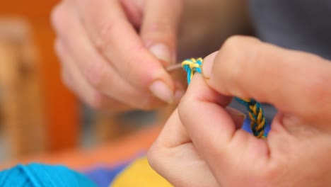 making bracelet - woman's hand knitting blue and yellow yarn, colors of ukrainian flag