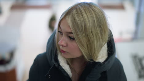 young woman riding a moving escalator in a mall, looking thoughtful, blurry background features people on the lower level, creating a peaceful yet dynamic urban scene with soft lighting