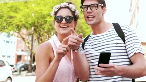 pareja de hipsters sonrientes apuntando hacia la dirección