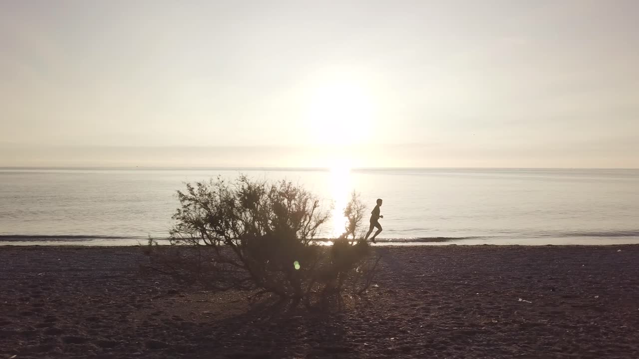 Young athlete runner man with fit strong body training on beautiful sunset at beach
