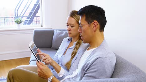 Couple-using-digital-tablet-while-relaxing-on-sofa