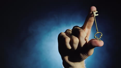 a man's hand holds a key against a dark background where fog swirls 4k video