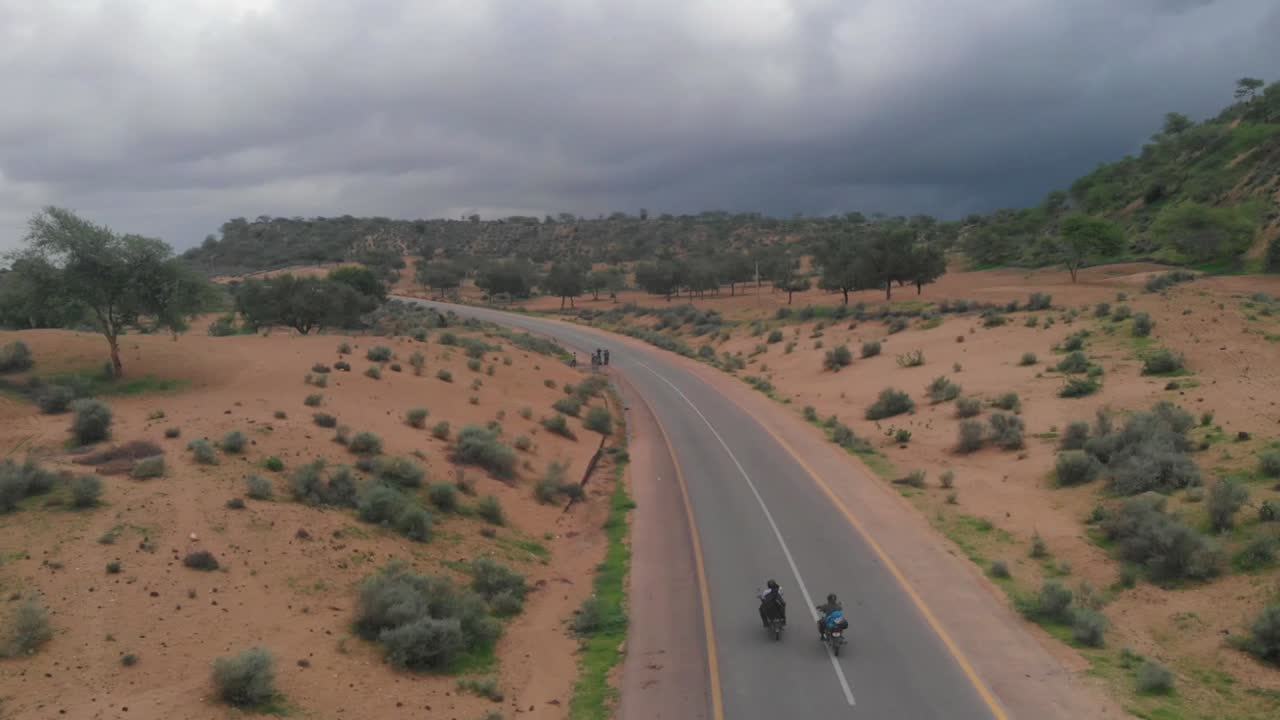 drone toma una toma aérea de la carretera en tharparkar ubicada en sindh donde dos motociclistas conducen su bicicleta