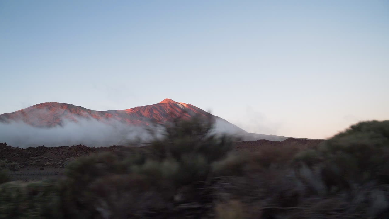 volcán el teide durante la puesta de sol con nubes bajas en su base, vista panorámica desde la ventana del camión
