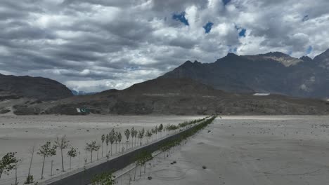 Aerial-View-Of-Sarfaranga-Desert-With-Empty-Road-Leading-Towards-Mountains-In-Background