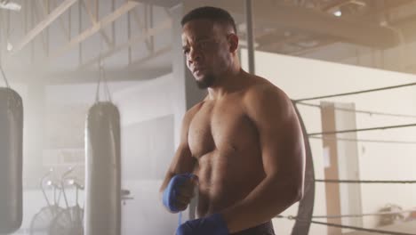 video eines fitten afroamerikanischen mannes, der sich auf ein boxtraining im fitnessstudio vorbereitet