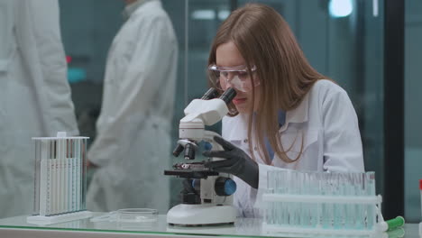 Pruebas-De-Laboratorio-De-Vacunas-Y-Medicamentos-Técnica-Femenina-Está-Viendo-Análisis-En-Investigación-De-Biología-Y-Virología-De-Microscopio