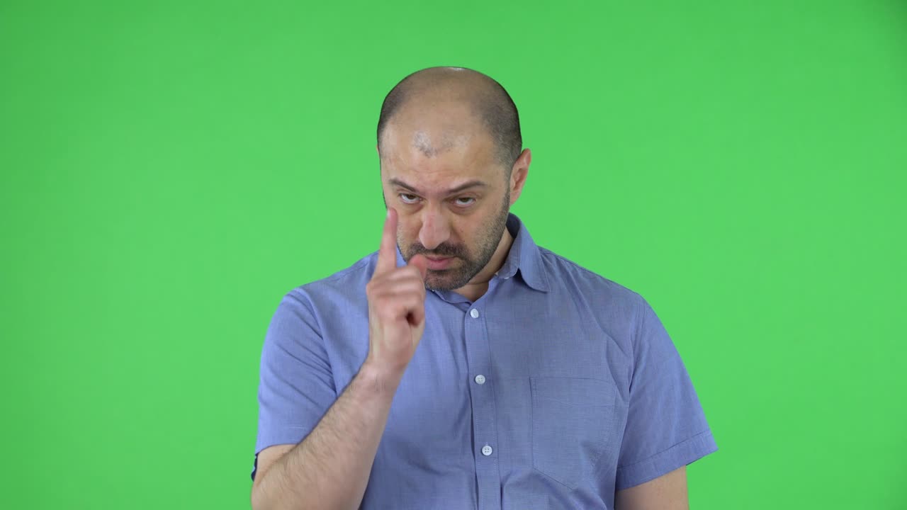 Portrait of middle aged men listening attentively, nods his head approvingly, points with a finger yes, you are right, for sure. Balding male with beard posing on green screen in the studio. Close up