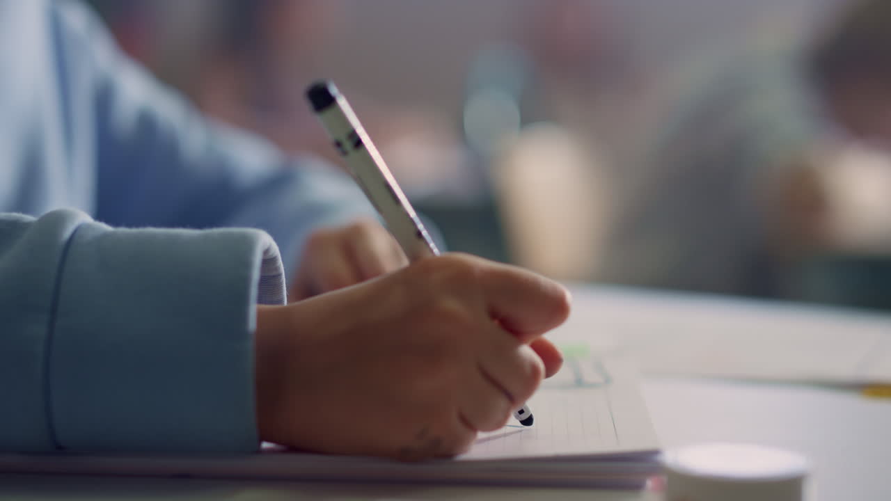Schoolgirl hand drawing in notebook at lesson. Student writing in exercise book