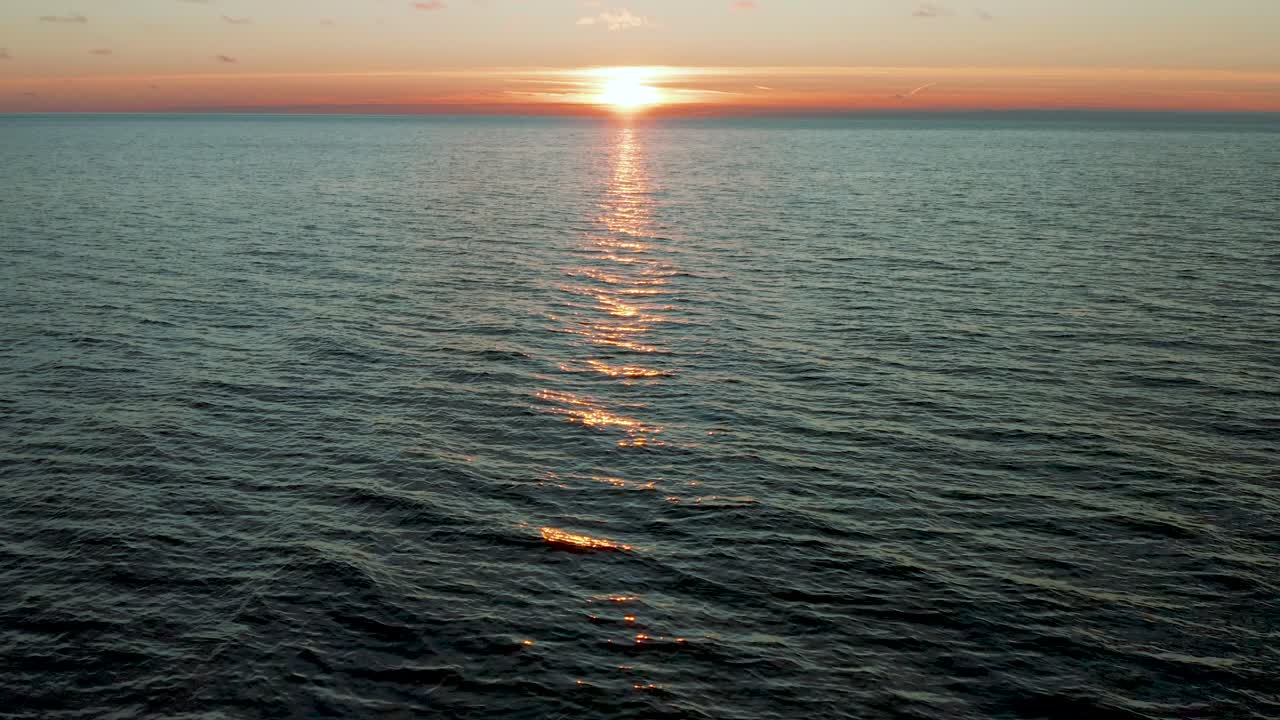 잔잔한 물결 모양의 바다 위로 날아가는 드론, 아름다운 일몰까지 카메라 기울기, 일출