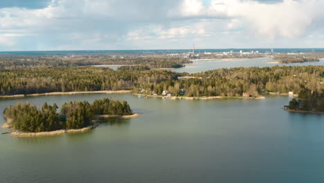 a drone flies in an arc pattern while fully displaying the beauty of a forested island set in a lake with blue sky and white clouds in the background.