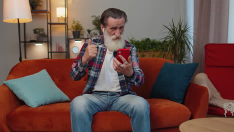 senior grandfather man making phone conversation call with family sitting on couch at home in room