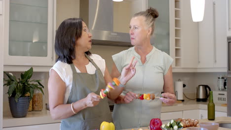 two diverse senior women preparing fresh vegetables in modern kitchen, enjoying cooking, at home