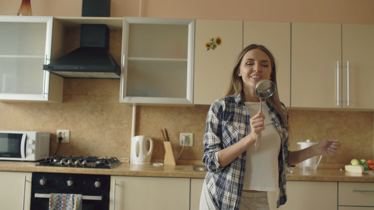 Donna che balla in cucina con utensili da cucina