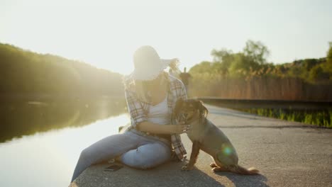 young woman relaxing by the lake with her dog