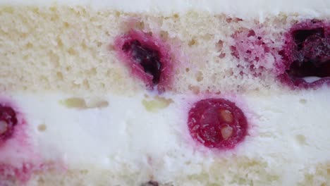 close up of a slice of white cake with red berries