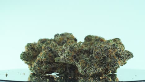 Close-up-shot-of-a-Marijuana-sativa-Super-Lemon-Haze-flowers,-yellow,-green-and-purple,-on-a-reflecting-360-rotating-stand,-Slow-motion-4K-video