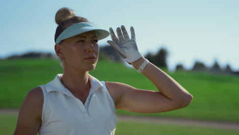 attractive lady playing golf at green course. woman looking around golfing field