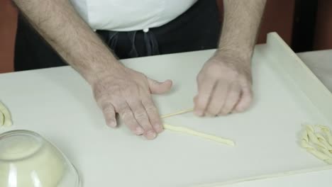 close up hands chef preparing traditional hand made italian pasta called busiate