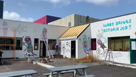 a painter works on a mural on a sunny day in astoria, or