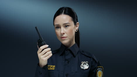 close up of the pretty policewoman talking in the walkie talkie and listening an answer while doing a work task