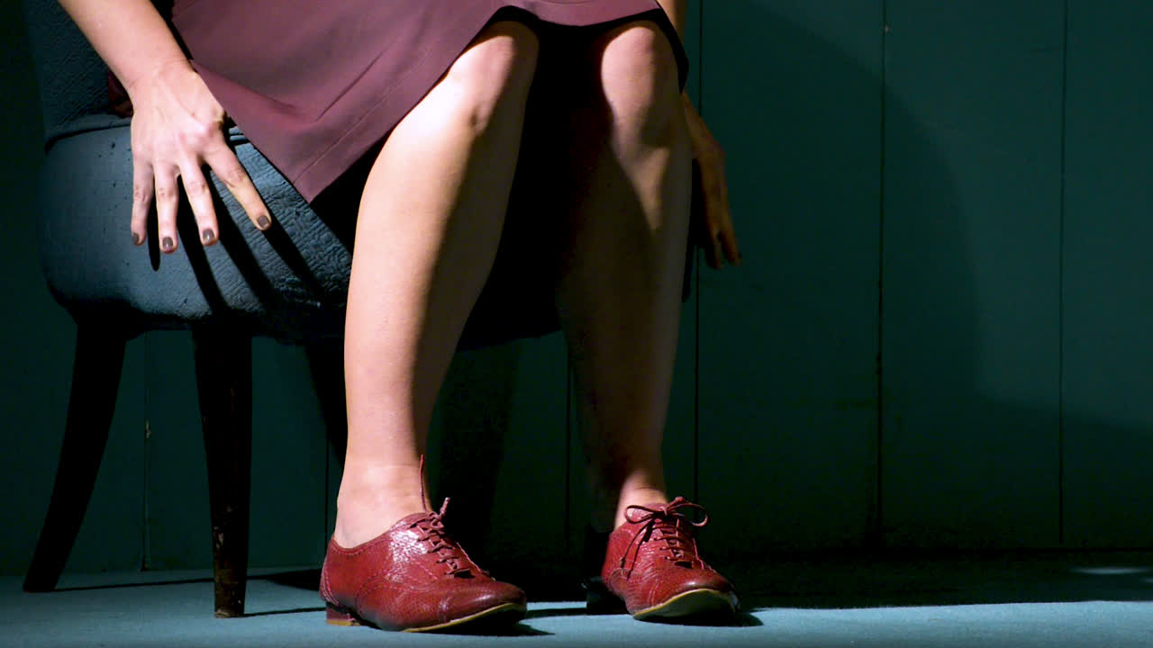 방에 있는 오래된 의자에 불안하게 앉아 있는 여자