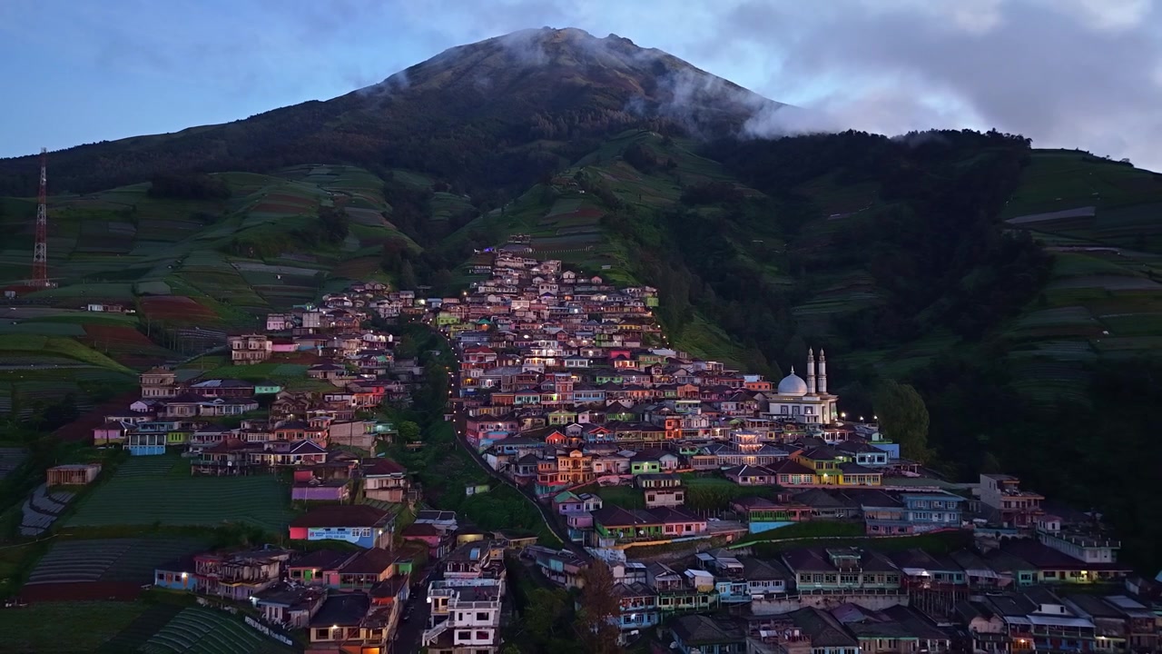 Poranny widok z lotu ptaka wioski Nepal van Java na górze Sumbing, przyćmione światło nad kolorowymi domami na zboczu wzgórza i mglisty krajobraz górski.