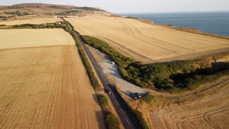 Circle-shot-aerial-view-of-a-road-on-Isle-of-Weight-where-you-can-spot-a-1973-classic-VW-parked-somewhere-far-in-the-car-park