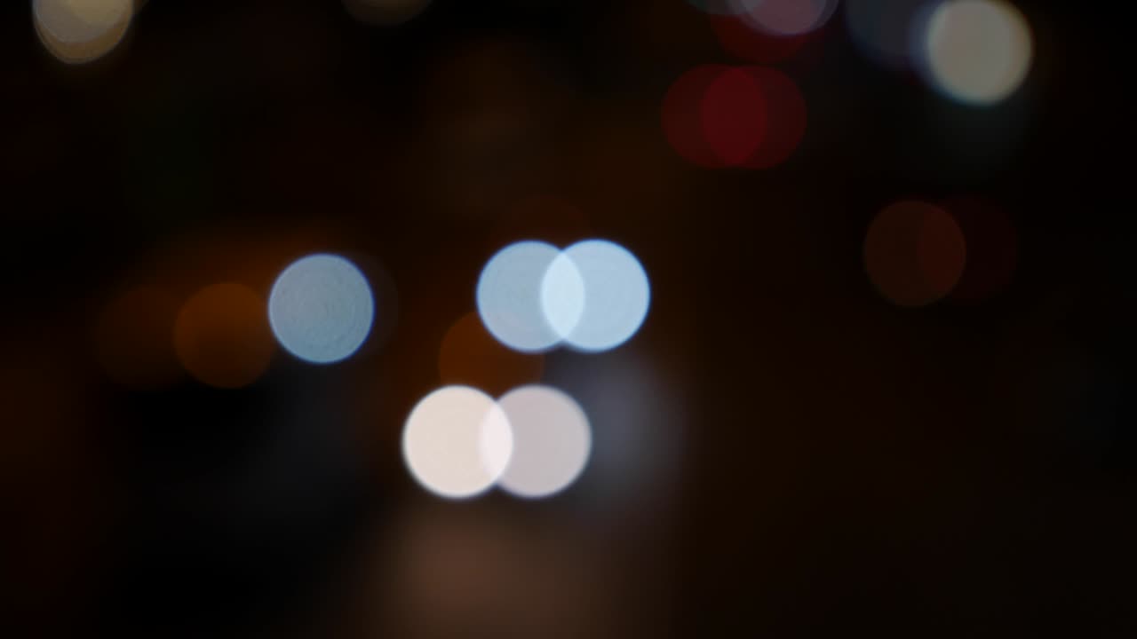 hermoso bokeh brillante en el fondo oscuro borroso por la noche. el redondo bokeh colorido brilla de las luces de los coches en la calle de la ciudad. fuera de foco con borroso. luces de la ciudad sin enfoque. bokeh de tráfico. concepto abstracto