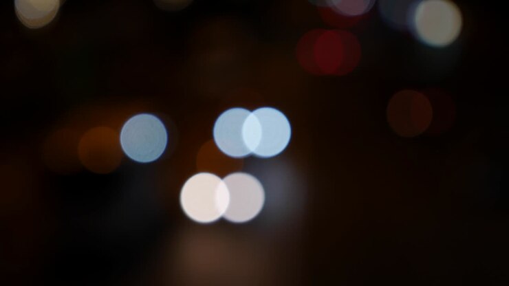 Beautiful glittering bokeh in dark blurry background at night. The round colorful bokeh shine from car lights on city street. Out of focus with blurry. Unfocused city lights. Traffic bokeh. Abstract concept