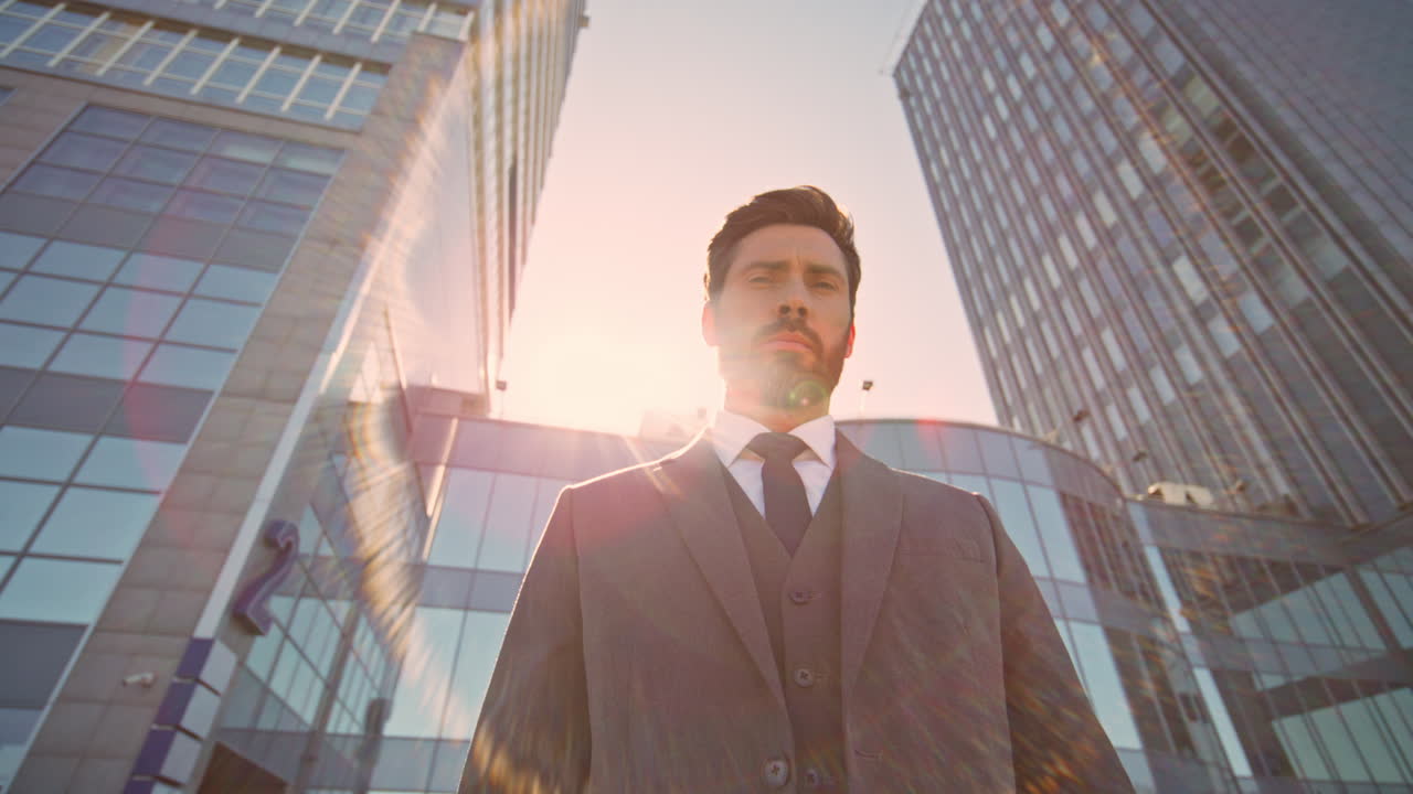 부유한 감독이 저녁 빛에서 시내에서 포즈를 취하고 있습니다. 심각한 사업가