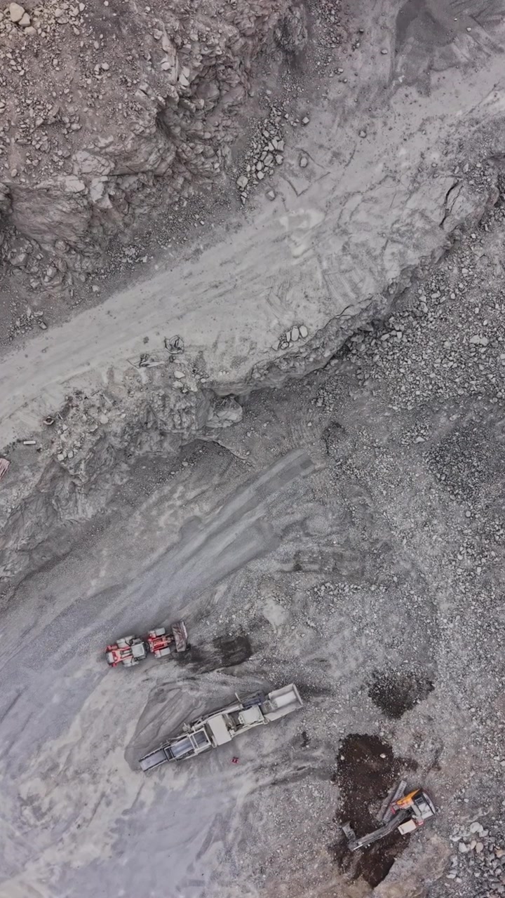 Vehicles move through a rocky industrial landscape by day