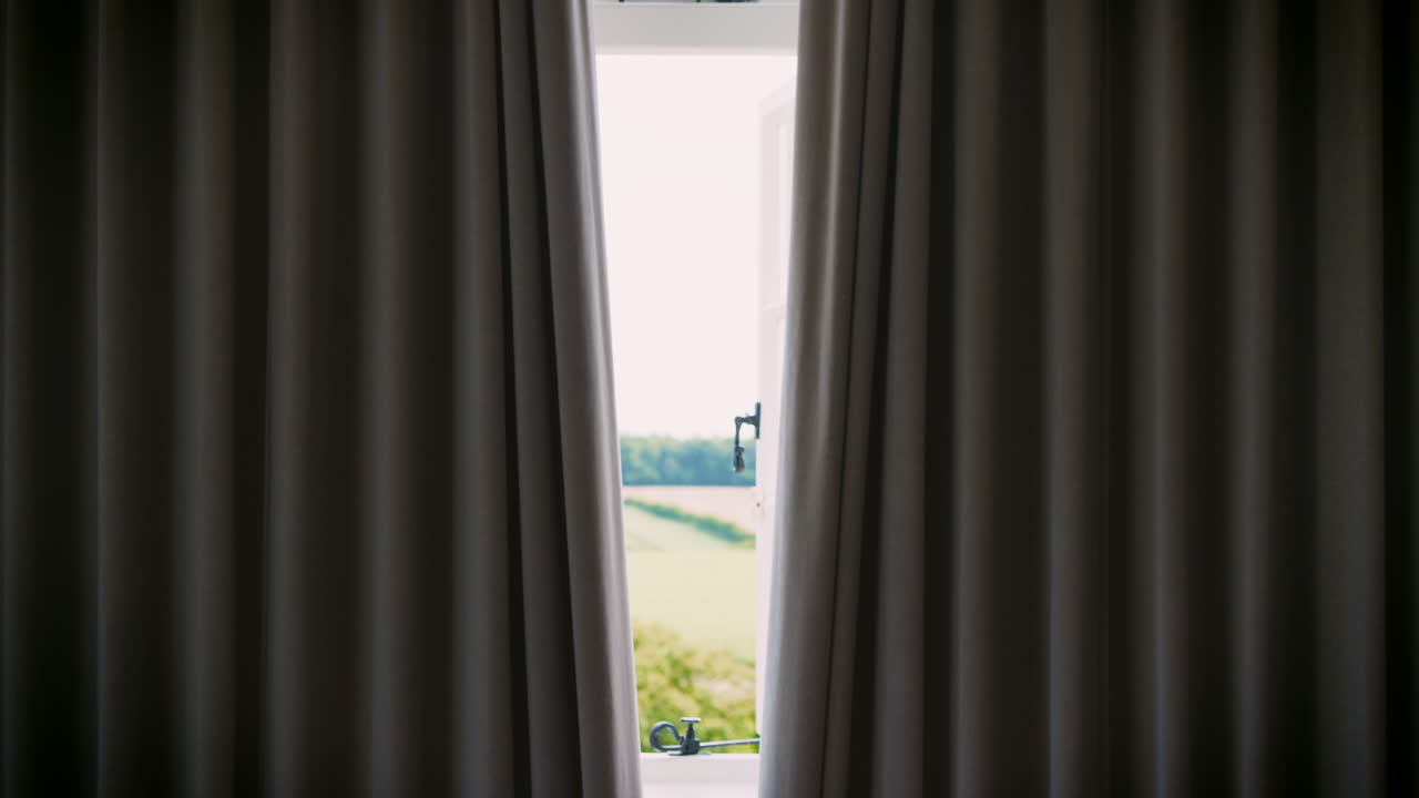 Tende della camera da letto aperte per rivelare la campagna attraverso la finestra