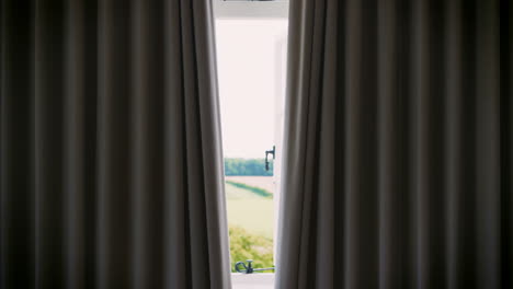 bedroom curtains open to reveal countryside through window