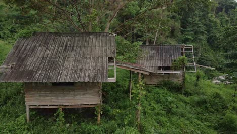 Absteigender-Drohnenblick-Auf-Thailändische-Holzbungalows-Im-Alten-Stil,-Die-Jetzt-Aufgrund-Der-Auswirkungen-Der-Covid-Pandemie-Auf-Reisen-Und-Tourismus-Verfallen-Und-Ungenutzt-Sind