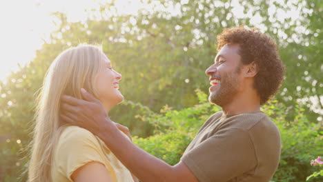 portrait of loving mature couple hugging outdoors against flaring evening sun