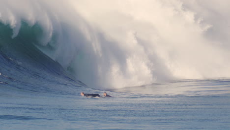 slow motion view of surfer at golden hour with strong light cast on white raging lip of foam from crashing wave