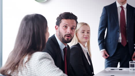 slow motion shot of young businessman speaking at meeting around boardroom table