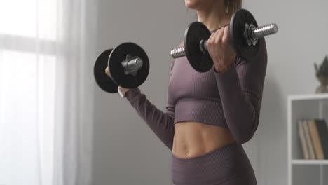una atleta delgada está entrenando con pesas en el hogar detalles de la aptitud corporal deportiva y el estilo de vida saludable levantando pesas para estar en buena forma