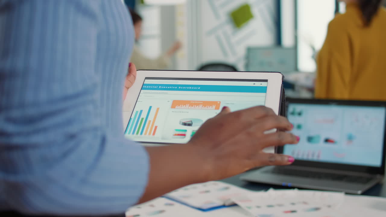 Closeup of african american woman hands picking up tablet interacting with touchscreen looking at erp software