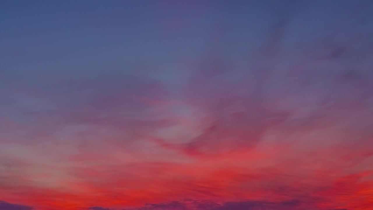 Sky colored from blue to red with clouds advancing in a timelapse
