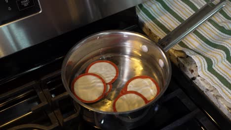 placing canning jar lids in hot water on the stove to heat up the seals - isolated