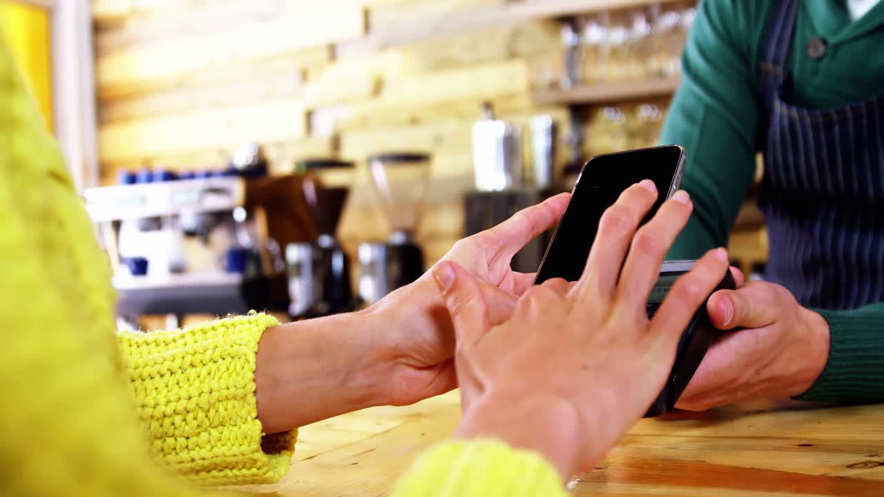 Woman paying bill through smartphone using NFC technology
