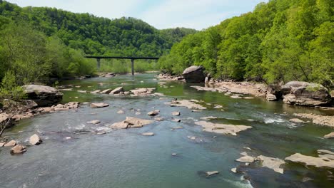 aerial fly along large flowing river with boulders, west virginia