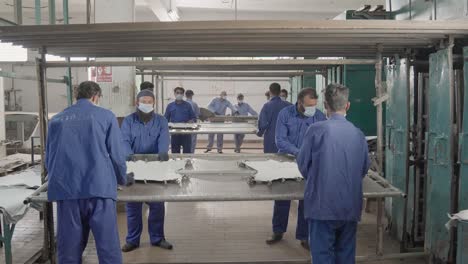 male workers in a leather factory processing animal hides on a stretching and drying rack.