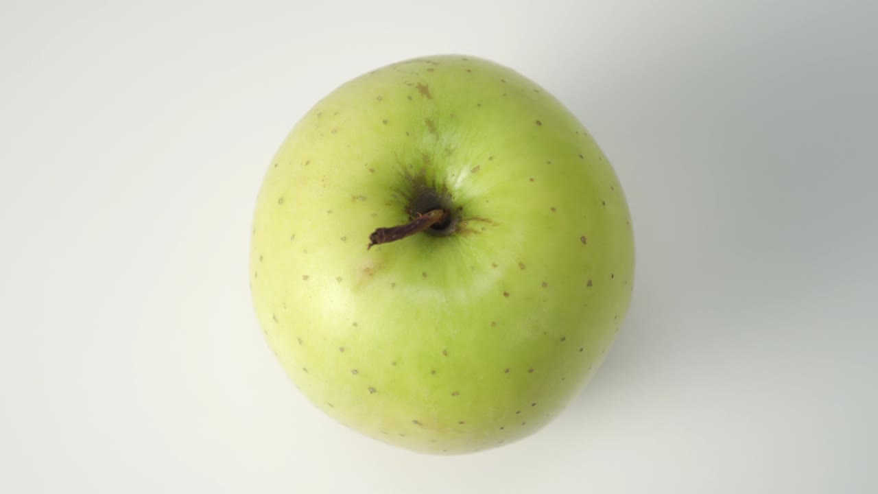 Modent grønt eple på hvit bakgrunn, nærbilde